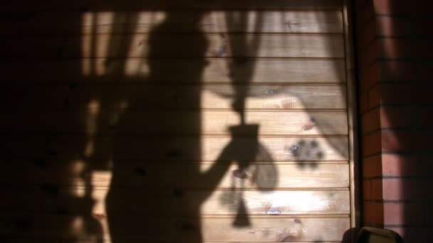 Schatten einer Person, die aus Becher an Wand trinkt — Stockvideo