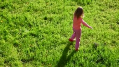 Yeşil çimenlerin üzerinde koşuşturan küçük kız
