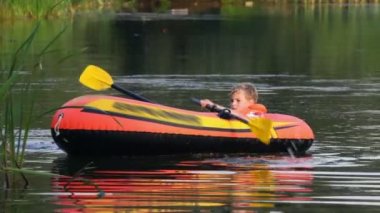 Göl kenarında bir şişme bot üzerinde çocuk dön