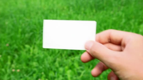 Male hand holding business card on grass — Stock Video