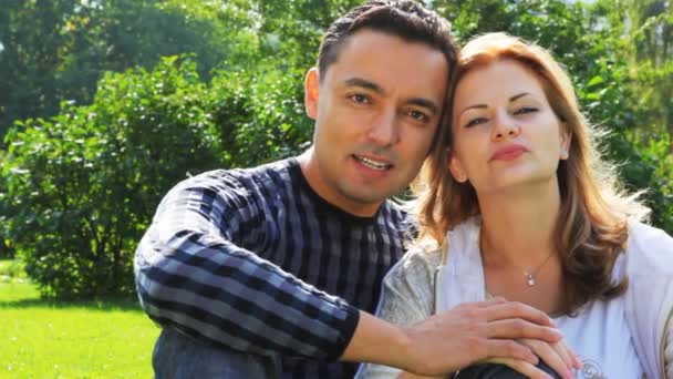 Couple assis dans le parc et regarder, femme avec bretelles — Video