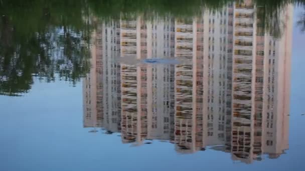 Gebäude spiegelt sich im Wasser, Gestein fällt ins Wasser — Stockvideo