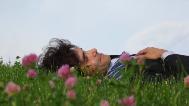 Felice bell'uomo sdraiato su erba verde e fiori di campo — Video Stock