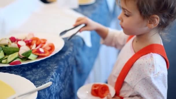 Pequeña niña coloca parte del tomate en el plato — Vídeos de Stock