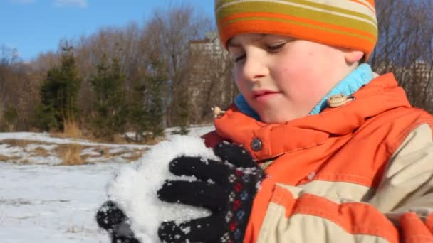 Мальчик делает снежок — стоковое видео