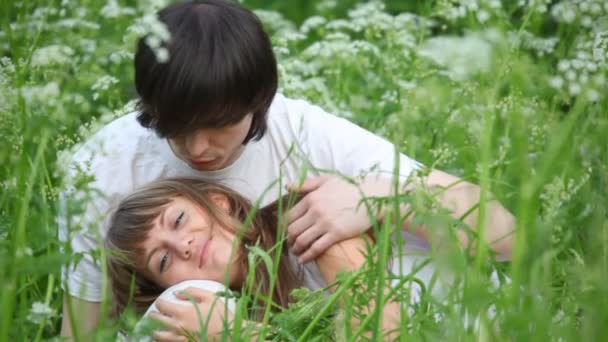 Young man and girl laying on grass and playing with each other — Stock Video