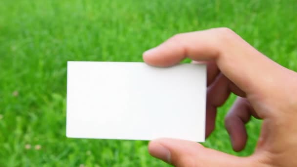 Male hand holding business card on grass — Stock Video