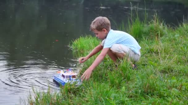 Menino obter brinquedo navio a partir de água — Vídeo de Stock