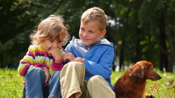 男孩和女孩坐在草地上的狗 — 图库视频影像