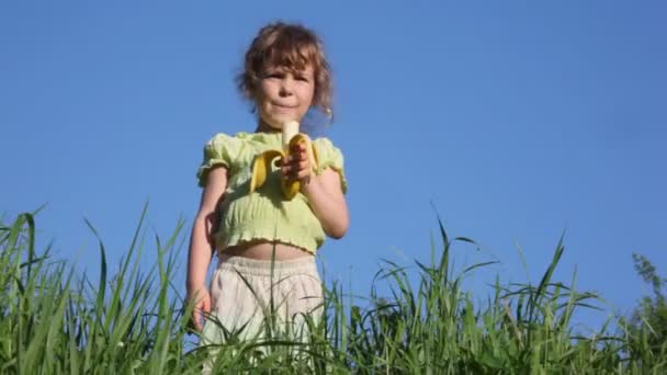 Mädchen isst Banane im Gras — Stockvideo