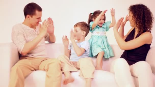 Family four with two children sit on sofa and play — Stock Video