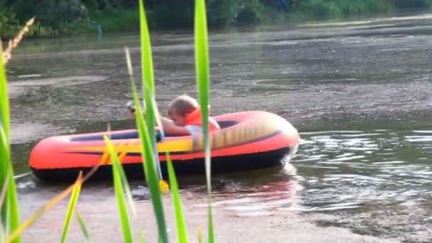 Jongen Roeien op een opblaasbare boot over meer — Stockvideo