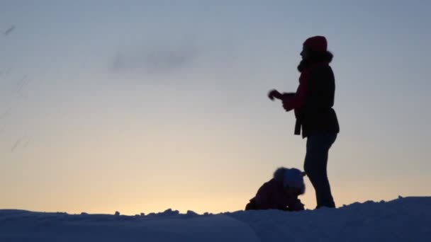 Силуэт мать с ребенком играть снег — стоковое видео