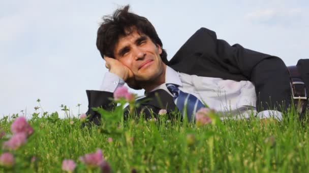 Happy handsome man lying and falling on green grass — Stock Video