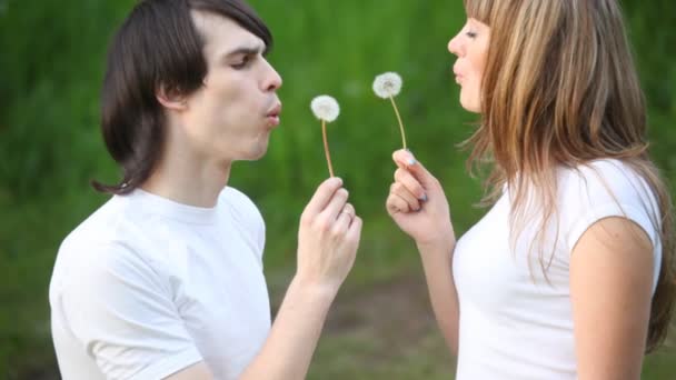 Młody człowiek i dziewczyna wydmuchiwania kwiaty, naprzeciw siebie — Wideo stockowe