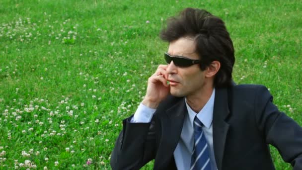 Pohledný muž s brýlemi slunce mluvit o telefonu — Stockvideo
