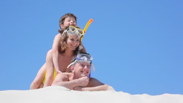 Пара пловцов и сын лежат на песке — стоковое видео