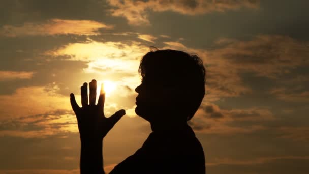 O homem passa as mãos pelo sol e reza a ele — Vídeo de Stock