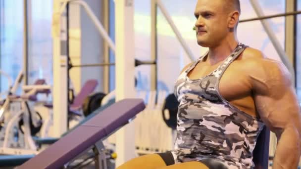 Bodybuilder exercising with dumbbells in gym — Stock Video