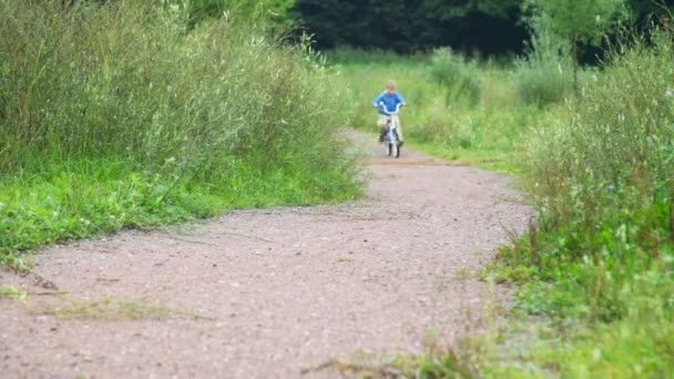 Мальчик катается на велосипеде в парке, на камеру — стоковое видео