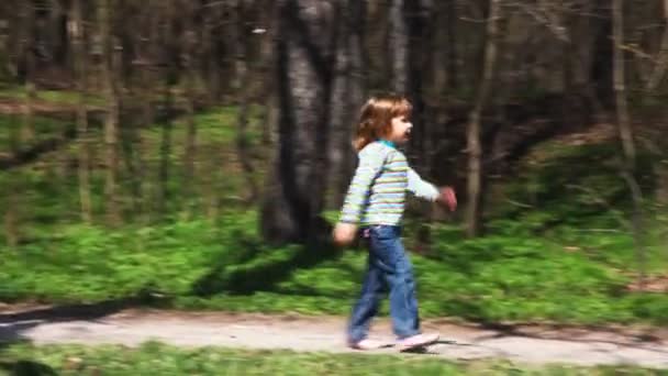 Mädchen geht im Frühjahr auf Waldweg auf Jungen mit Fahrrad zu — Stockvideo