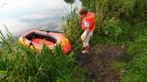 Junge zieht Schwimmweste an und setzt sich auf aufblasbares Gummi — Stockvideo