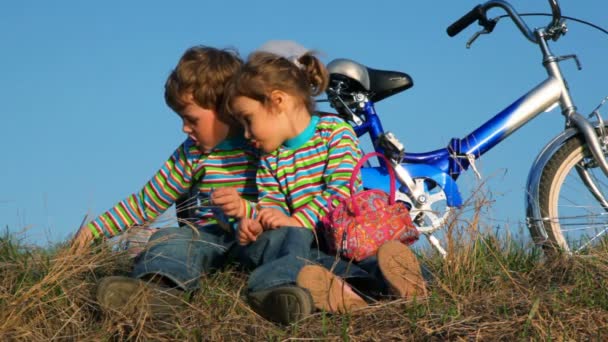 Chłopiec i dziewczynka siedzi na trawie ich gry — Wideo stockowe