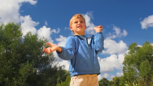 Boy throwing up blue balloon in park — Stock Video