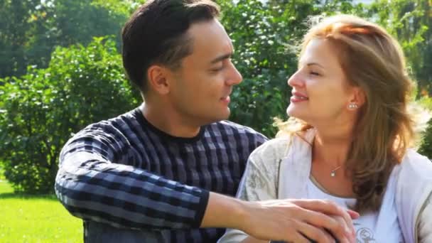 Couple sits in park and talk, woman with braces — Stock Video