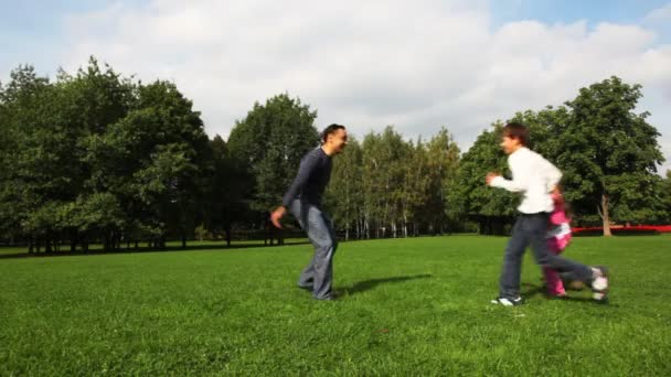 Мужчина превращает мальчика и девочку в поле в парке — стоковое видео