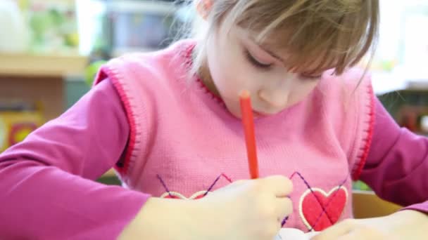 Mädchen sitzt im Klassenzimmer, sie nimmt einen blauen Softtip-Stift und beginnt zu zeichnen — Stockvideo