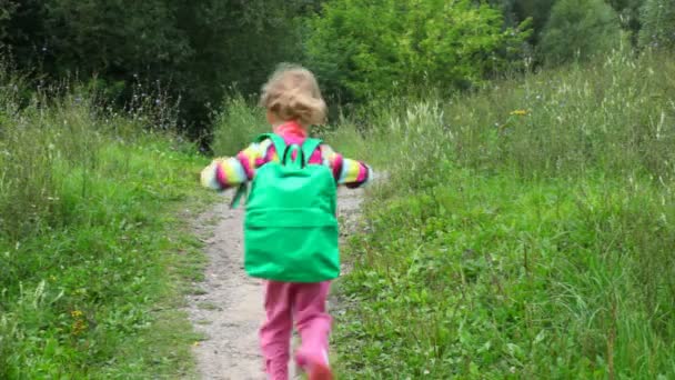Little girl with rucksack running in park from camera — Stock Video