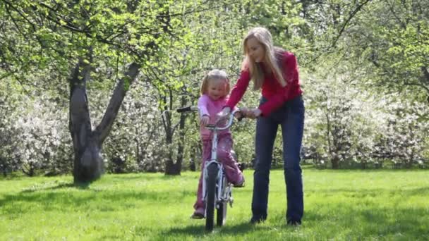 Девушка учится сидеть на велосипеде — стоковое видео
