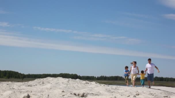 Familj av fyra körs på sand — Stockvideo