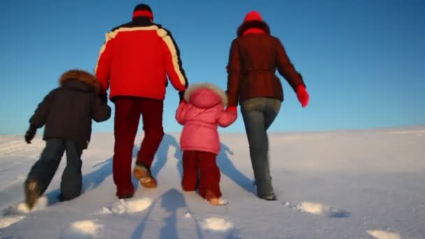 Promenade familiale derrière sur la colline de neige au coucher du soleil — Video