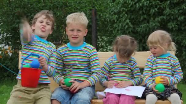 4 děti sedí na lavičce a házení míče — Stock video