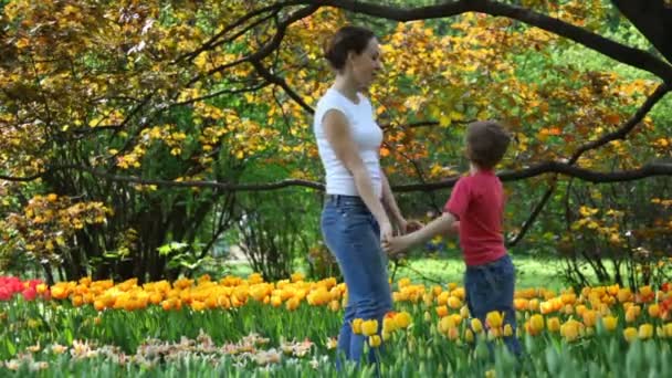 Madre con figlio nel parco autunnale vicino ai tulipani — Video Stock