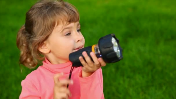 Niña con antorcha eléctrica en el parque — Vídeo de stock