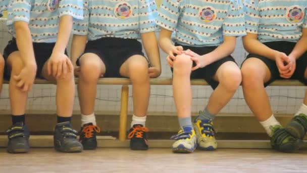 Kinder sitzen auf der Bank in der Sporthalle — Stockvideo