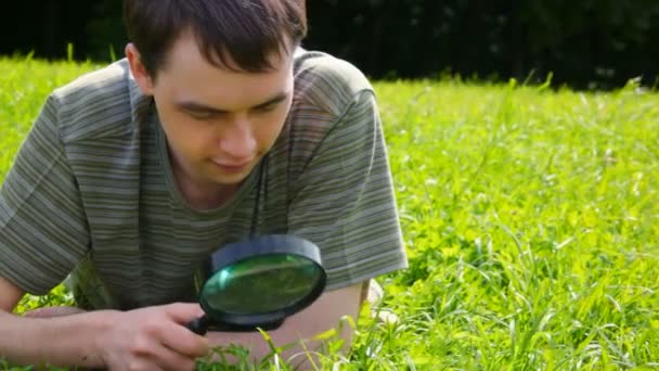 Young man looks through a magnifying glass — Stock Video