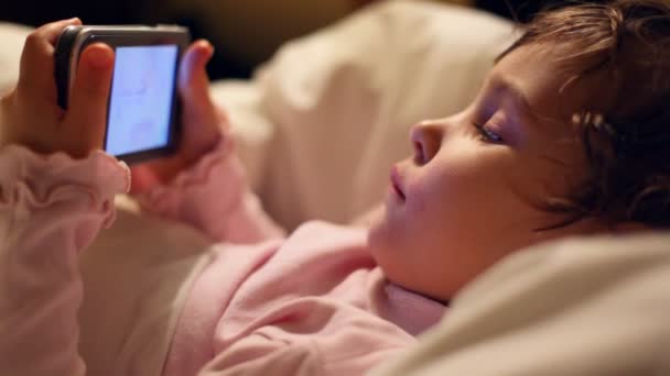 Kleines Mädchen liegt in Betten, blickt auf Handfläche und lächelt — Stockvideo