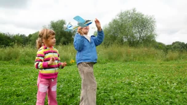 Boy and girl flying toy aircraft and running behind him — Stock Video