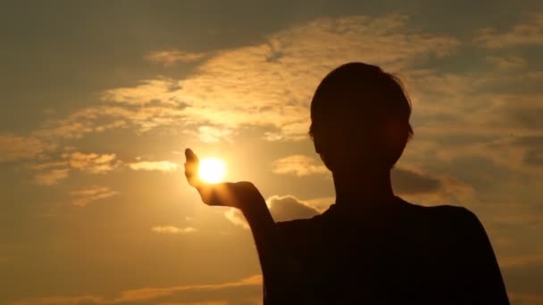 Silhouette of man which has taken away sun in hand — Stock Video