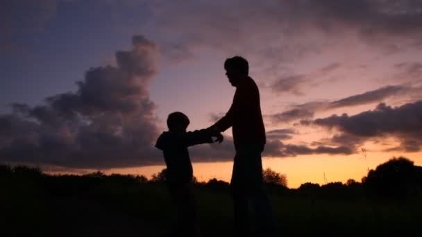 Vater rotiert mit Sohn vor Sonnenuntergang — Stockvideo