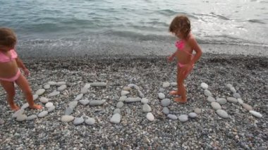 iki küçük kız taş pebble Beach plaj yazıt üzerinde yürüyüş