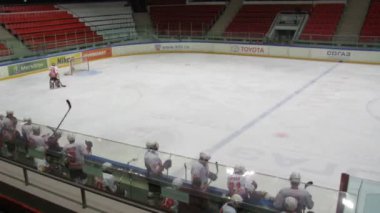 On ice the hockey match: players in the white and red form, a hall is empty. 