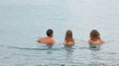 familia de tres personas de pie en el mar y plaiying con agua, unir las manos