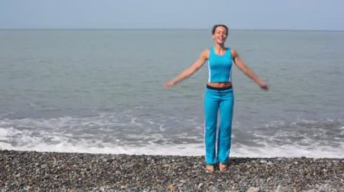 pebble beach, deniz arka planda üzerinde egzersiz mutlu bir genç kadın