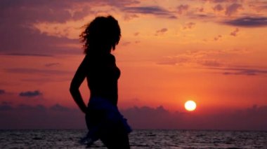 plaj ve arka planda gökyüzü günbatımı deniz üzerinde dans eden genç kadın silüeti