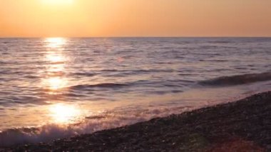 pebble beach, deniz ve gün batımı gökyüzü arka planda çalışan genç çocuk